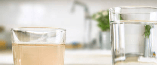 Close up of two clear glasses. One with clear liquid, and one with dirty liquid.