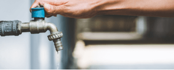 Close up of a hand turning a faucet