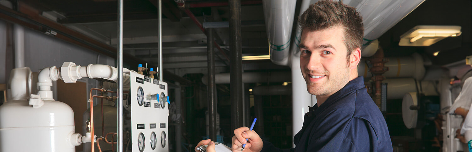 A worker smiling at the camera in front of machines.