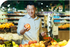 A man holding an apple in the grocery store.