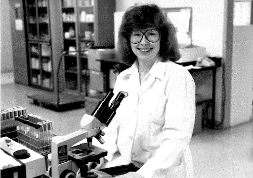 A woman in a labratory smiling from the 1960s