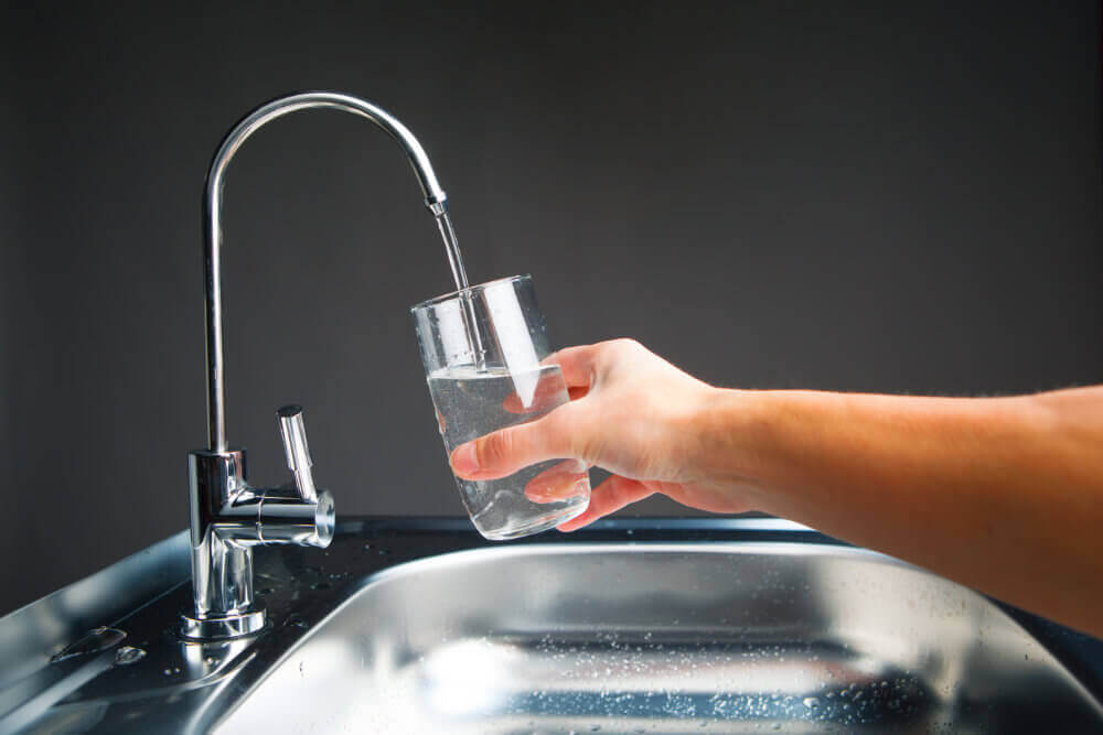 A hand filling up a glass with water.